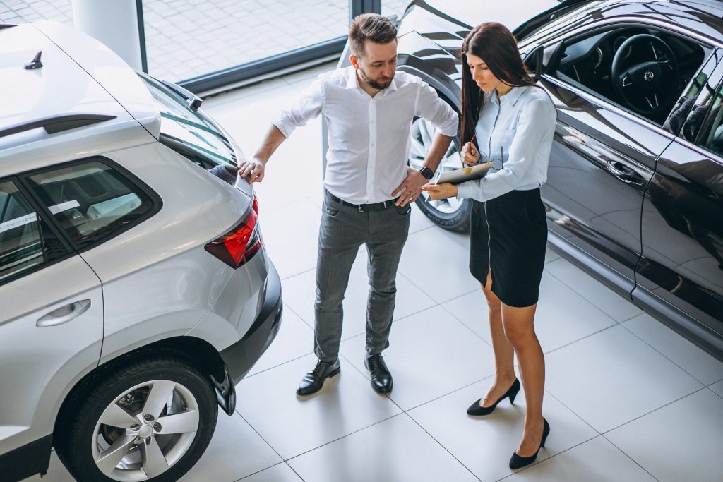 Empresário escolhendo carro com vendedora em um salão de automóveis